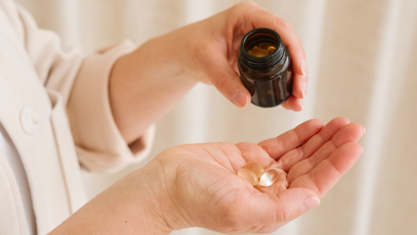 Main versant des capsules d'omega 3 depuis un flacon